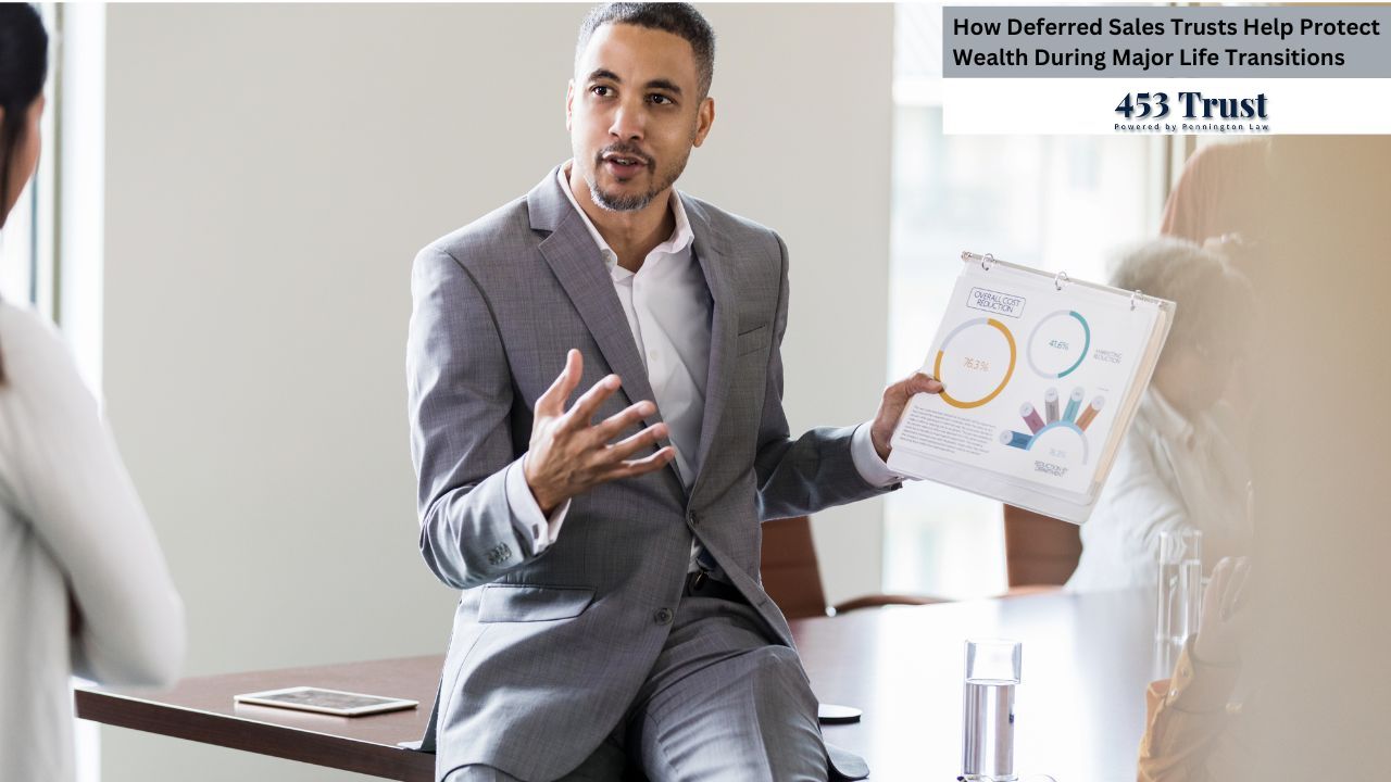 A businessman is presenting financial charts to a client during a meeting. The image shows a medium-close-up shot of a dark-skinned man in a gray suit sitting on the edge of a table, gesturing animatedly with his hands as he holds up a financial report featuring pie charts and bar graphs.