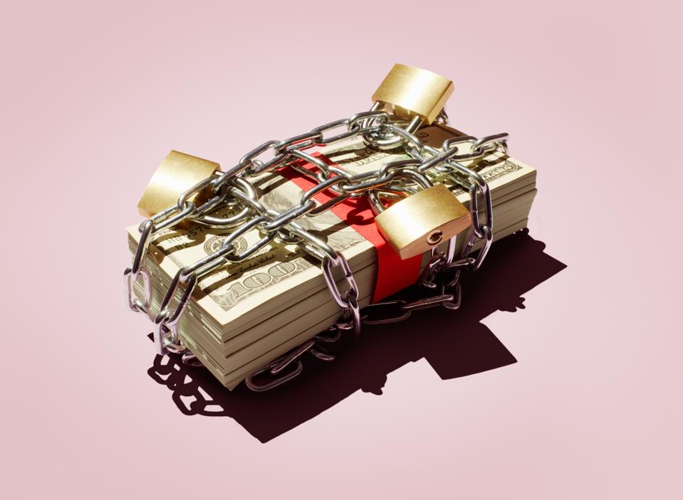 A stack of hundred-dollar bills is secured with a metal chain and padlocks, symbolizing the safeguarding of wealth.