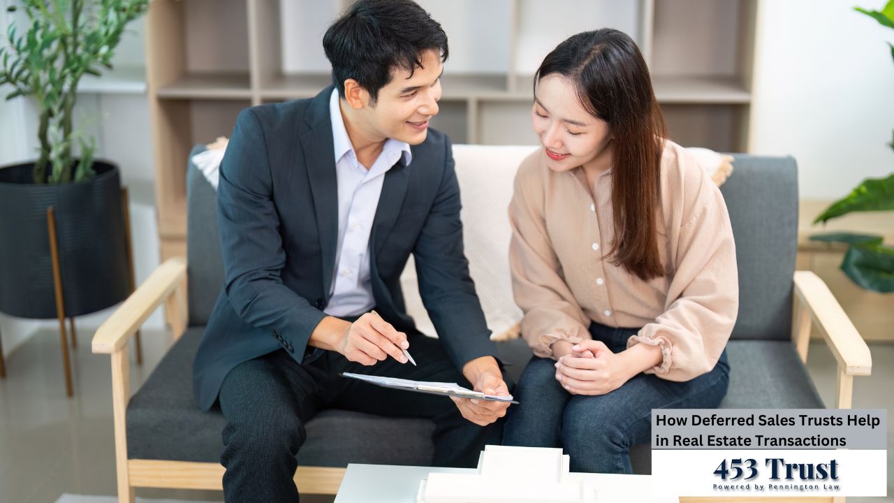 The image features a man in a suit discussing paperwork with a woman, both smiling, while seated on a modern couch in what appears to be a relaxed and professional setting.